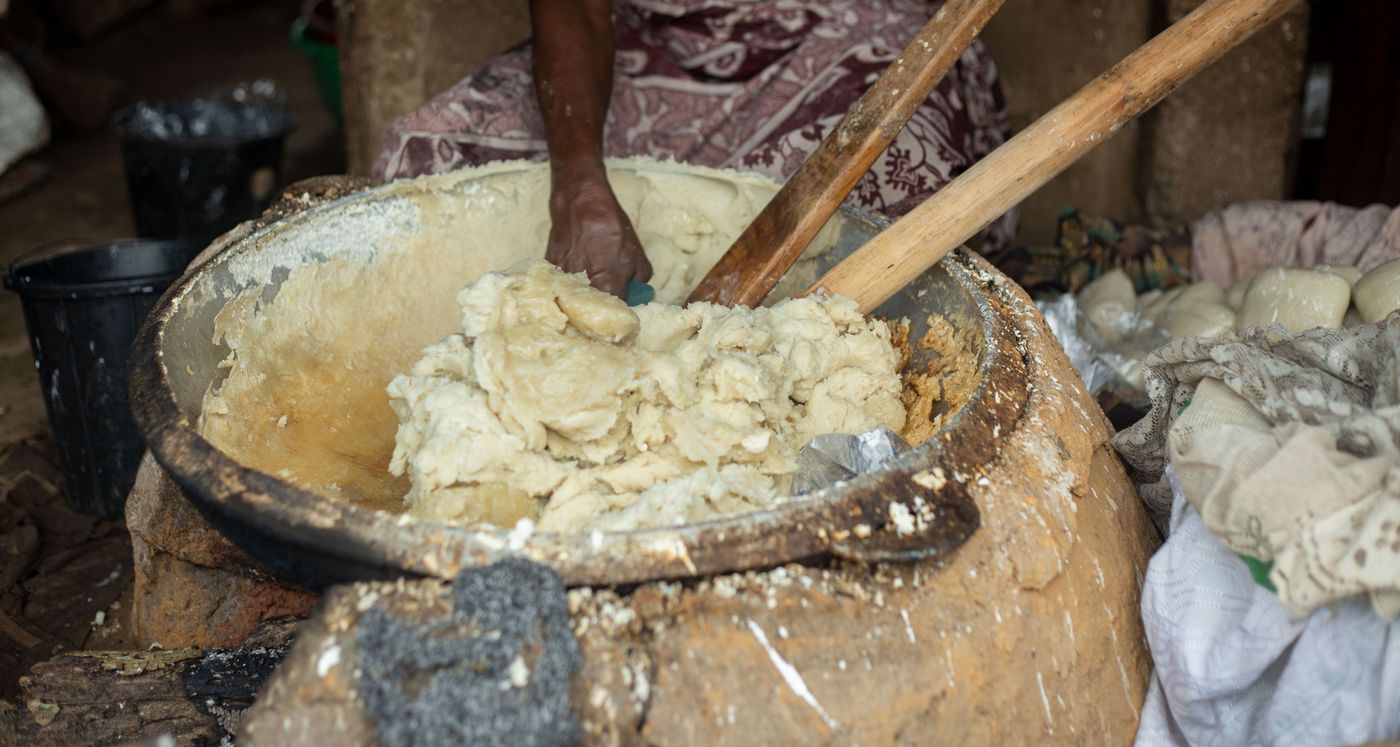 Gros plan sur une pâte de beurre de karité ivoire pétrie à la main dans une grande bassine