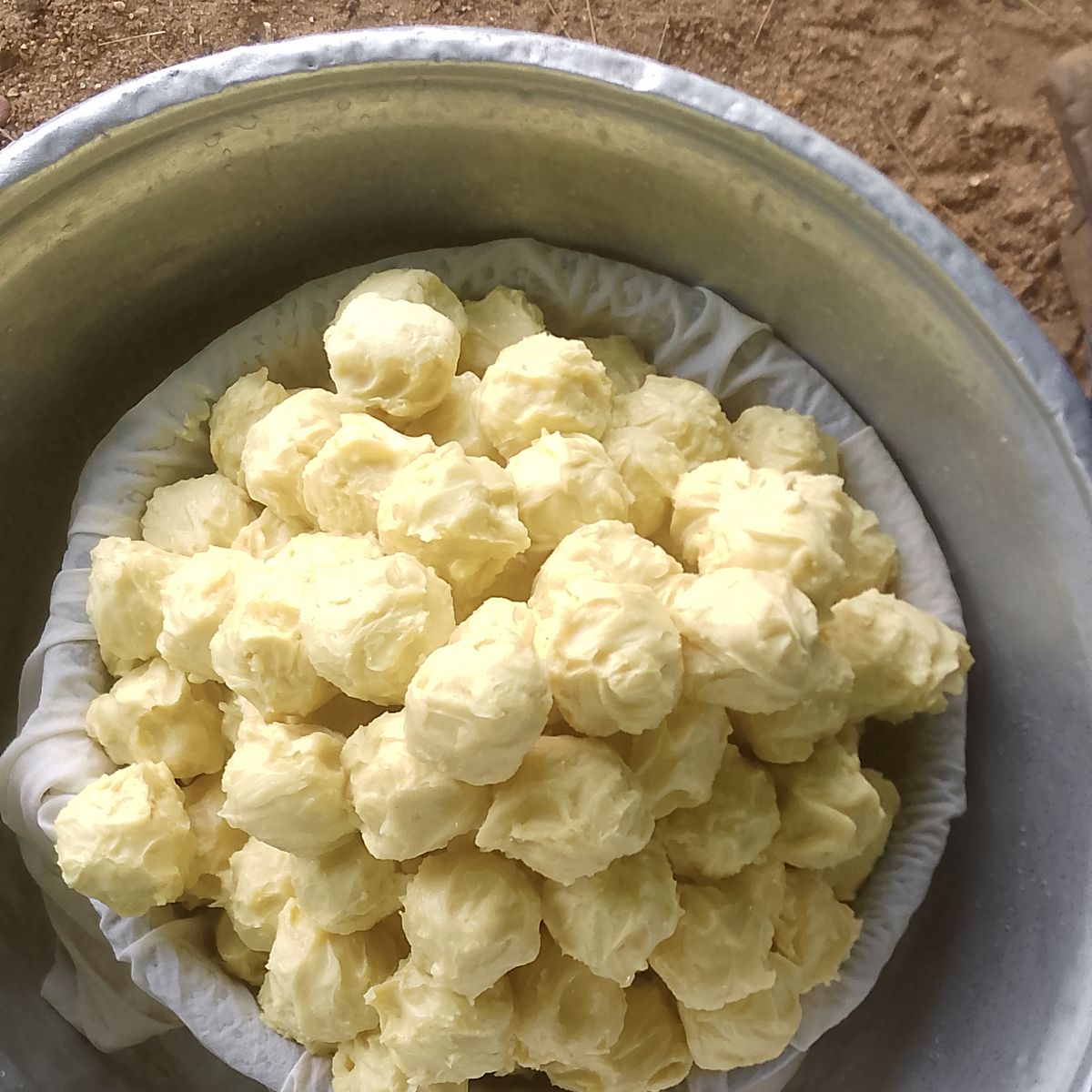 Boules de beurre de karité ivoire façonnées à la main dans une bassine en métal