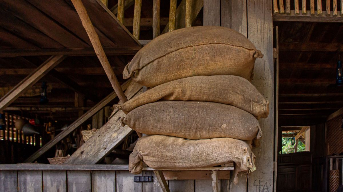 Quatre sacs de toile de jute pleins empilés dans une grange en bois