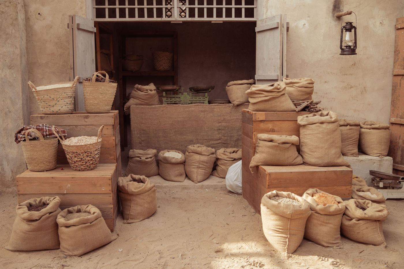Sacs de toile de jute remplis de grains et paniers tressés devant une échoppe